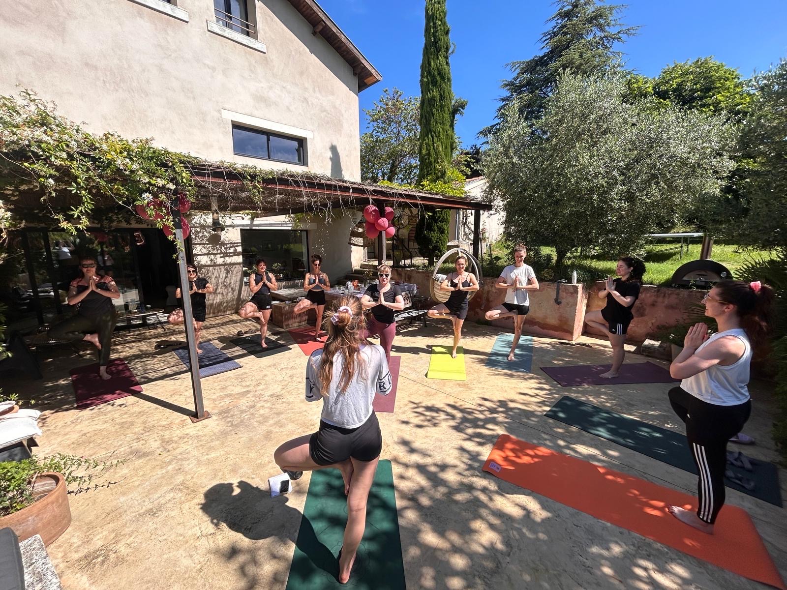 Cours de yoga collectif en extérieur, plusieurs participants en posture de l'arbre